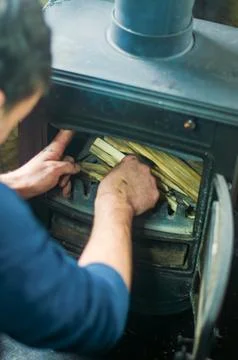 Close-up man making fire sitting floor by fireplace in countryside house Stock Photos