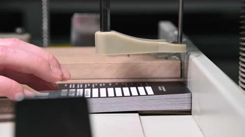Close-up of a man making a puncture on printed and cut labels for products in Stock Footage 165914597