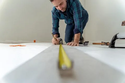 Close up of man measuring the floor to install wooden decking in his house Stock Photos