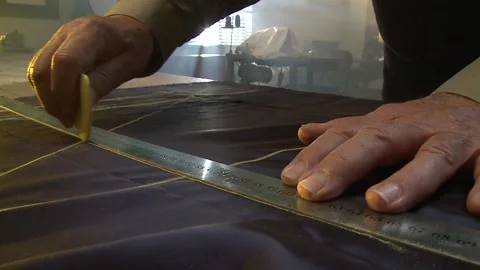 A Close-up of a man measuring out fabric with a ruler and clover chalk Stock Footage 311924077
