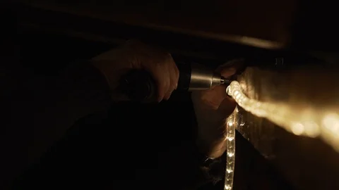 Close-up of a man mounting exterior lights with an electric screwdriver Stock Footage 100889976