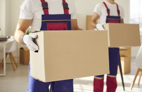 Close up of man mover worker holding a cardboard box in hands standing in new Stock Photos
