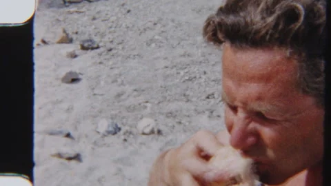 Close-Up Of Man Munching Peach Beside Tent On Sandy Beach Stock Footage 322133943