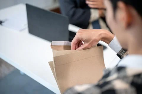 Close up of a man opening brown envelope and taking document out at working.. Stock Photos