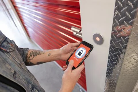 Close up man opening storage facility locker with mobile phone app Stock Photos
