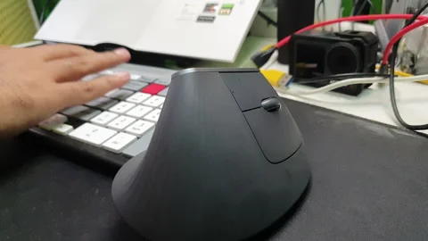 Close up of man operating a mouse and typing on a keyboard on a messy desk Stock Footage 234960376