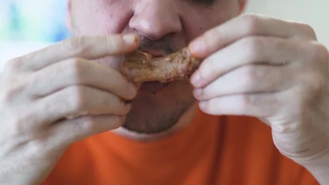 Close Up Man in Orange Sweater Eating Succulent Pork Ribs Unhealthy snack Stock Footage 306648680