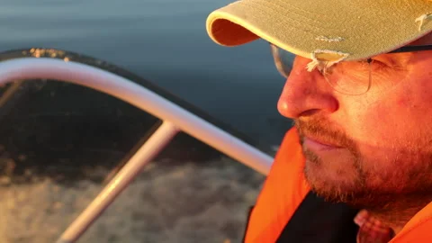 Close-up of a man in an orange vest floating in a boat on a river Video stock 283462514