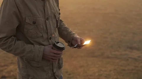 Close up man outdoors using mobile phone and scrolls the tape. Guy drinking Vídeo Stock 112300241