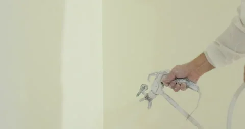 Close up of man painter paints the walls with paint spray gun. Airless spray Stock Footage 242597127