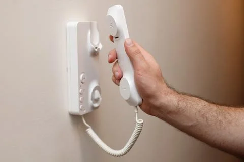 Close-up of a man picking up an intercom phone Stock-Fotos