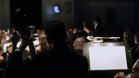 Close-up man playing double bass. A group of violinists in orchestra during a Stock Footage 108489036