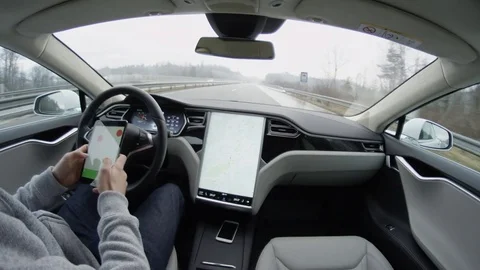CLOSE UP Man playing games on tablet in self-driving automated Tesla Model S car Stock Footage 72839559