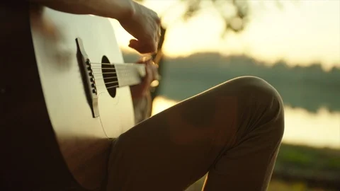 Close up of man playing guitar at sunset Stock Footage 98680095