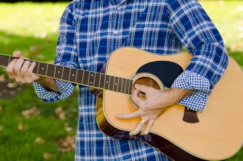 Close up of man playing a guitar without showing his face. Stock Photos