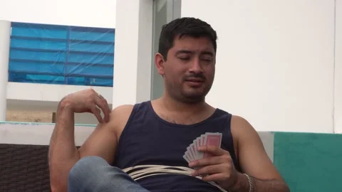 Close-up of a man playing playing cards with his hands and listening to his Video stock 155813994