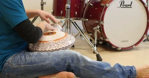 Close up of a man playing the Udu in front of a drumset Stock Footage 104459070