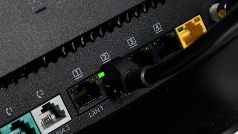 Close up of man plugging Ethernet cable into a Fibre broadband modem Stock Footage 104019976