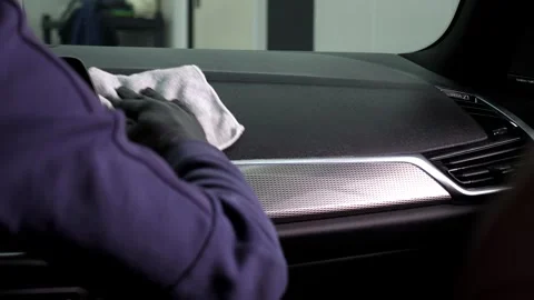Close-up of a man polishing a shiny black car with microfiber in a car showroom. Stock Footage 314604825