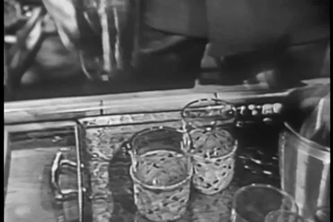 Close-up of man pouring beverage into small glasses, 1950s 스톡 동영상 35327736