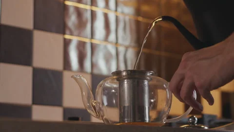 Close-up of a man pouring boiling water into a teapot with tea leaves Stock Footage 294256488