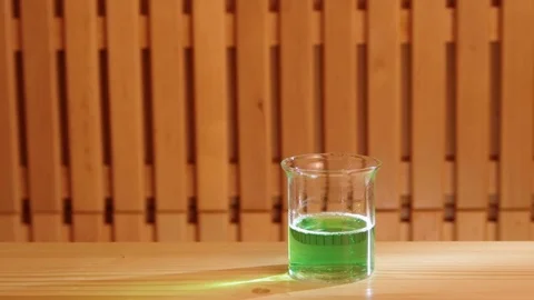 Close-up on a man pouring green liquid from syringe into glass cup studio light Video stock 77409479