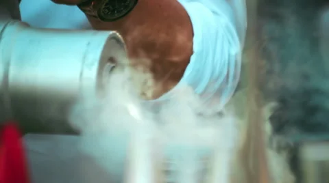 Close-up of a man pouring liquid nitrogen in a metal thermos and waving his h Video stock 66821294