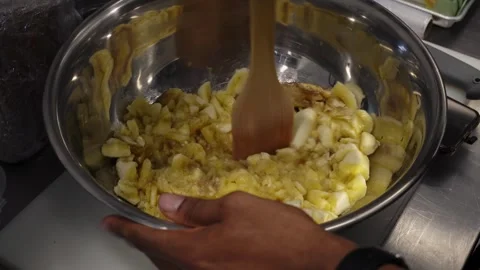 Close-up of a man preparing banana puree with a wooden spatula in a metal plate Stock Footage 272821895