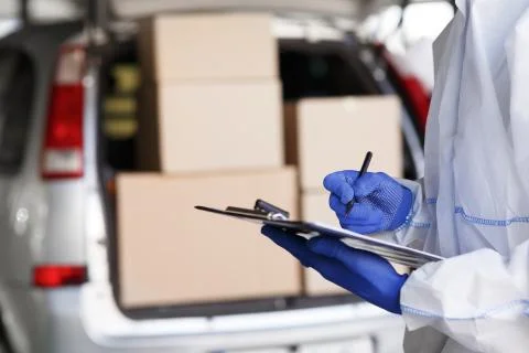 Close up of man in protective suit checking delivery in list Photos