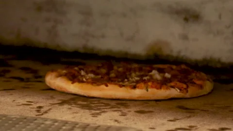 Close up of man pulling a freshly baked Pizza out of a Pizza Oven using a pizza  스톡 동영상 137530933