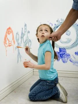 Close-up of a man pulling a girl's top while painting on a wall Stock Photos