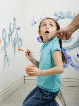Close-up of a man pulling a girl's top while painting on a wall Stock Photos