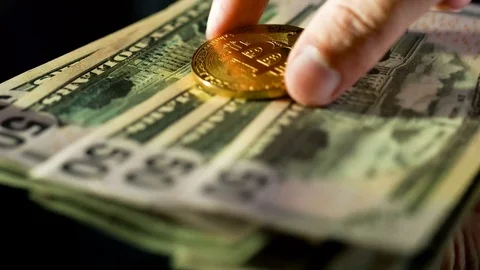 Close up of man puts a golden bitcoin on a dollar banknotes Stock Footage 79761402