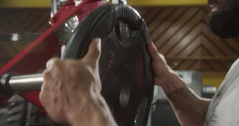 Close-up man puts metal disc on sports projectile for strength training Stock Footage 123534821