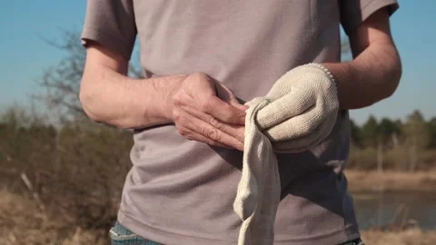 Close up man puts protective work gloves on his hands. work uniform. slow motion Stock Footage 249882423
