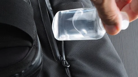 Close-up. Man puts Small bottle Sanitizer in a black modern backpack. Stock Footage 128850081