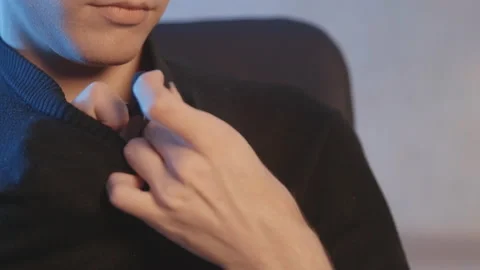 Close-up. A man puts on a wire lavalier microphone, adjusts his jacket. Vidéo 204074059