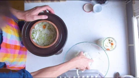 Close-up of a man putting chopped cabbage in a fermenting crock pot Vídeos de archivo 76140011