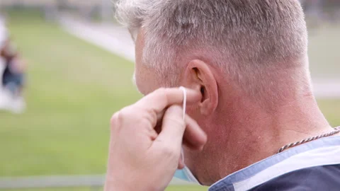 Close up of man putting on a face mask in a park during coronavirus. Stockbeeldmateriaal 131287469