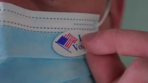 Close Up of Man Putting I Voted Sticker on PPE Face Mask After Voting Stock Footage 141214128