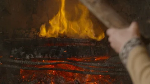 Close up of man putting log into fireplace in slow motion Stock Footage 143019289