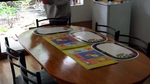 Close-up of a man putting placemats on the dining table for lunch in the daytime Stock Footage 164621952