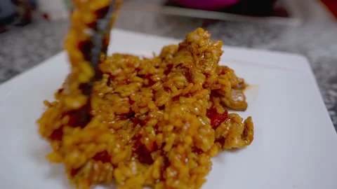 Close up of man putting a portion of the paella on a white square plate Stock Footage 163925887