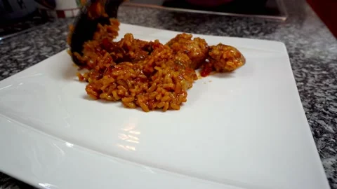 Close up of man putting a portion of the paella on a white square plate Stock Footage 163925901