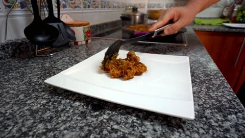 Close up of man putting a portion of the paella on a white square plate Stock Footage 163925911