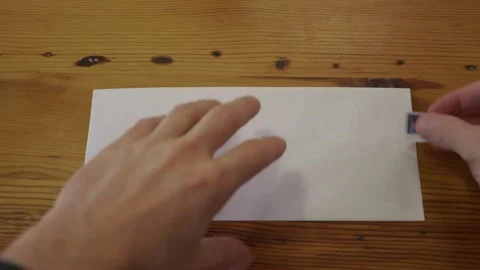 Close Up of a Man Putting a Stamp on a Blank Envelope Stock Footage 148593145