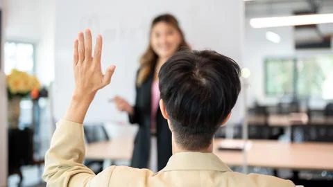 Close up man raising hand asking question to woman speaker after explaining.. Stock Photos