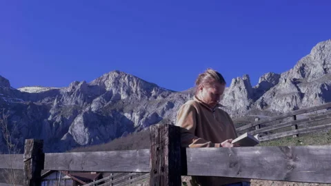 Close up of man reading book with scenic mountain backdrop Stock Footage 336623007