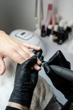 Close-up of a man receiving a manicure procedure. A nail technician in black Stock Photos