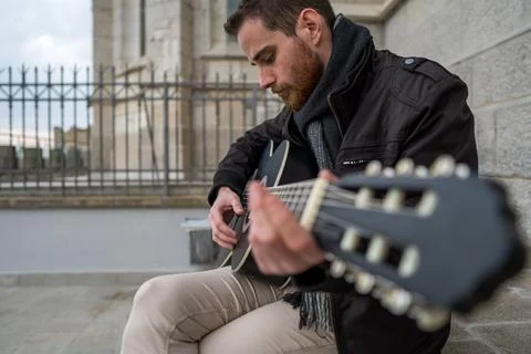 Close-up of a man with red beard learning to play the guitar alone in an empt Stock Photos